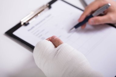 Bir kişinin sağlık sigortası Form doldurma kırık el ile yüksek açılı görünüş
