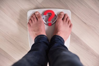 Kırmızı ile ağırlık ölçekte duran kişinin ayak işareti işareti soru