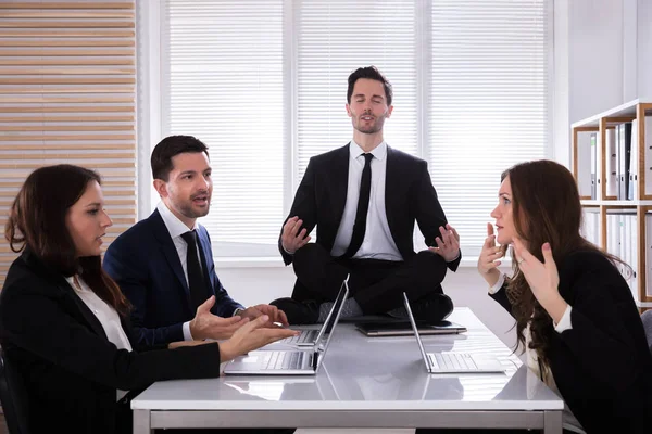 Επιχειρηματίας Διαλογισμό Ενώ Συνάδελφοί Του Έχοντας Συνομιλία Στο Γραφείο — Φωτογραφία Αρχείου
