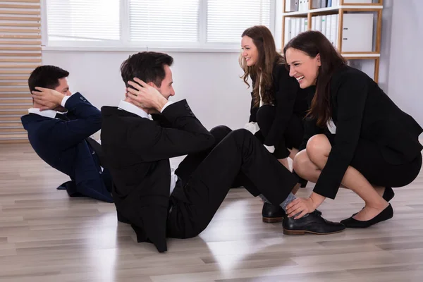 Jovens Empresárias Felizes Assistindo Colegas Masculinas Enquanto Fazem Exercício Local — Fotografia de Stock