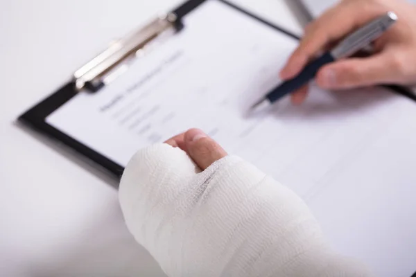 High Angle View Person Fractured Hand Filling Health Insurance Form — Stock Photo, Image