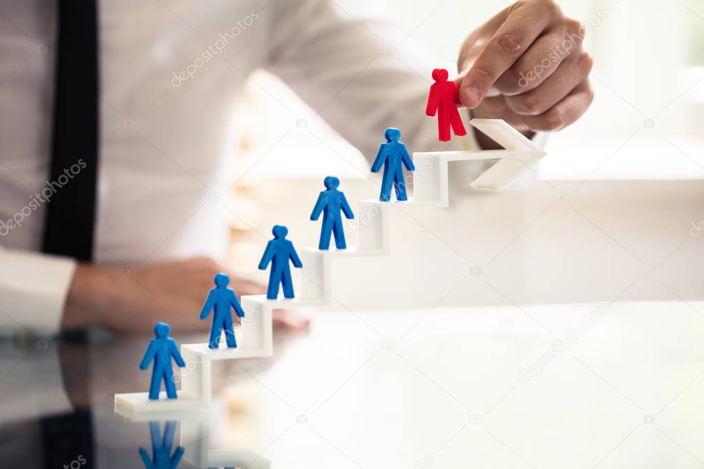 Businessperson Picking Red Human Figure From Staircase Made Of Arrow