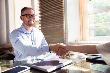 Genç işadamı işyerinde ortağı ile el sallayarak gülümseyen