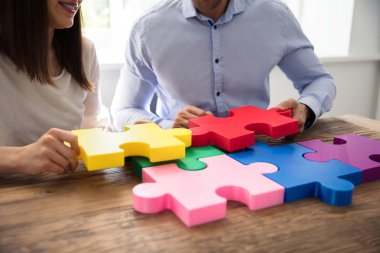 İki iş adamları üzerinde ahşap Resepsiyon çok renkli parçalı bulmaca çözme