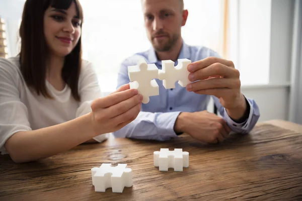 Close Two Businesspeople White Jigsaw Pieces Wooden Desk — Stock Photo, Image