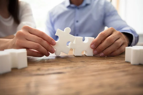 Close Two Businesspeople White Jigsaw Pieces Wooden Desk — Stock Photo, Image