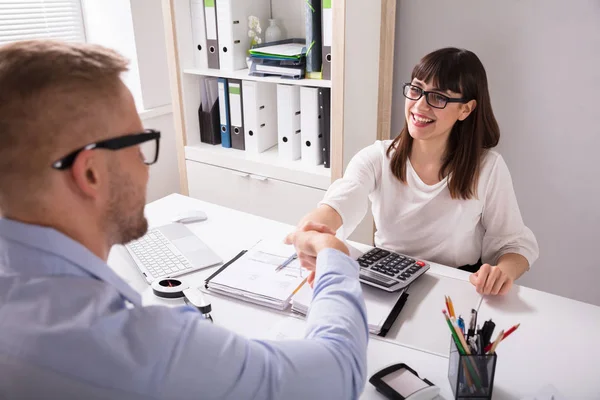 İşyerinde Resepsiyon üzerinde mali danışmanı ile el sallayarak istemci gülümseyen