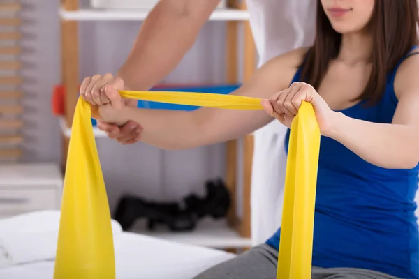 Fisioterapeuta Assistindo Mulher Enquanto Fazendo Exercício Com Faixa Exercício Amarela — Fotografia de Stock