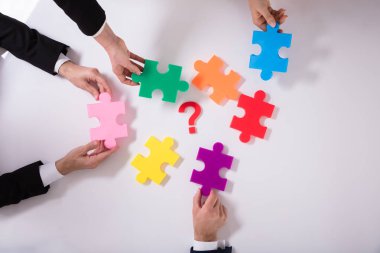 Parçalı bulmaca soru işareti ile beyaz arka plan üzerinde tutarak işadamları grubu