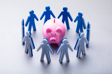 Elevated View Of Human Figures Surrounding Pink Piggybank On White Background clipart