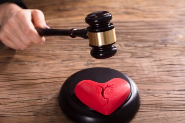 Close-up çekiç çarpıcı yargıç önünde kırmızı bir kırık kalp