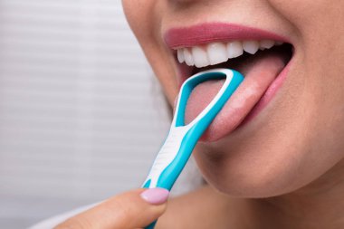 Close-up Of A Woman Cleaning Her Tongue With Cleaner clipart
