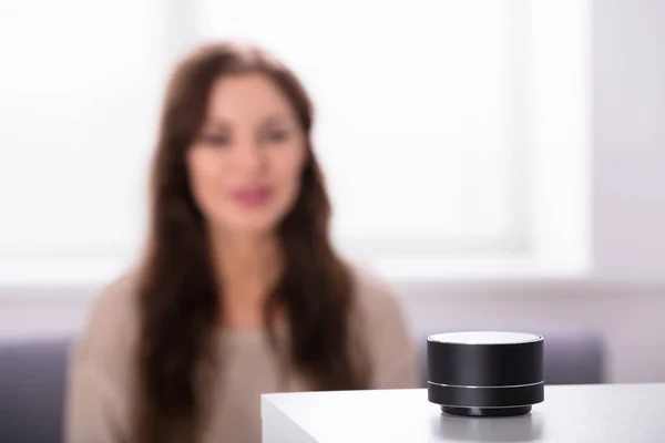 Woman Listening To Black Wireless Speaker On Furniture