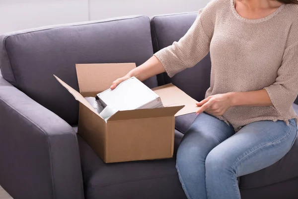 Lächelnde Junge Frau Sitzt Auf Sofa Und Packt Empfangenes Paket — Stockfoto