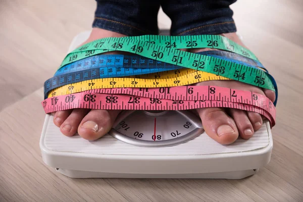 Крупный План Ступни Человека Шкале Веса Обернутой Разноцветной Измерительной Лентой — стоковое фото