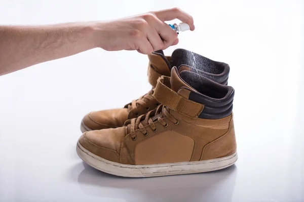 Mano Del Hombre Esparciendo Desodorante Zapatos Malolientes Contra Fondo Blanco — Foto de Stock
