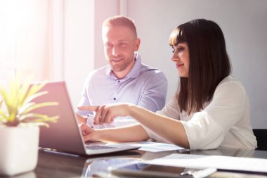 Ofiste dizüstü bilgisayar üzerinde çalışan iki genç iş adamları