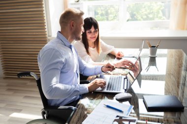 İş yerinde dizüstü bilgisayarda çalışan iki genç iş adamı