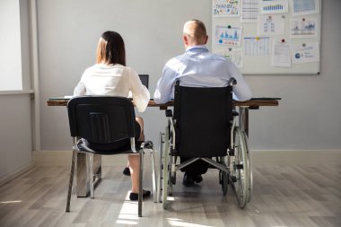 Arkadan Görünüş üstünde Laptop çalışma meslektaşı ile Engelli iş adamı