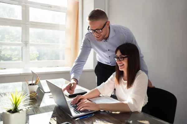 Bir şey üstünde Laptop ortağında Office için gösterilen genç mutlu işadamı