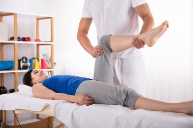 Bacak masaj fizyoterapist tarafından alma yatakta yatan genç kadın