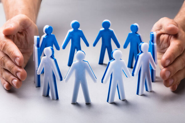 Крупный план "Рука человека, защищающая человеческие фигуры"
