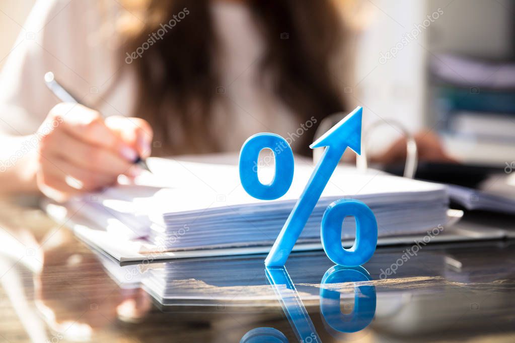 Close-up Of Blue Percentage Symbol In Front Of Businessperson Working On Document
