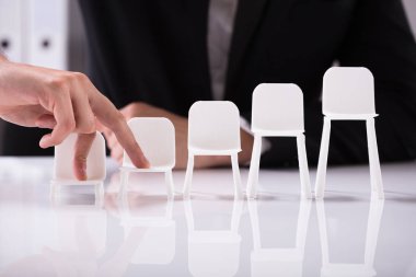 Yansıtıcı arka plan üzerinde sandalye parmak boyutunu artırma üzerinde yürüme işadamı