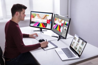 Genç erkek tasarımcı çizim grafik tablet bilgisayarda çalışırken yan görünüm