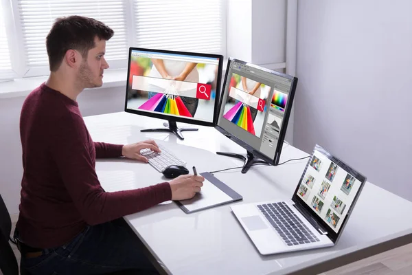 Genç erkek tasarımcı çizim grafik tablet bilgisayarda çalışırken yan görünüm