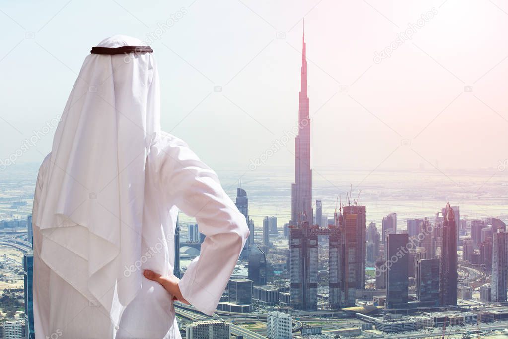 Rear View Of A Arabic Man Outstretching His Hand At Modern Buildings In Dubai