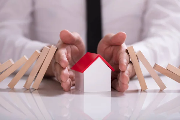 Närbild Näringsidkares Hand Skydda Husmodell Från Faller Träklossar Vita Skrivbord — Stockfoto