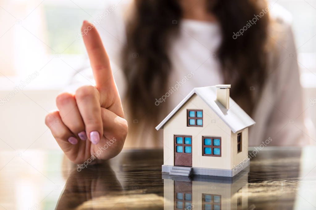 Close-up Of A Businesswoman Gesturing No Sign Near House Model On Desk