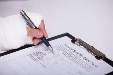 Bir kişinin kırık el Beyaz arka plan üzerinde tıbbi yararı talep formu doldurma ile yakın çekim