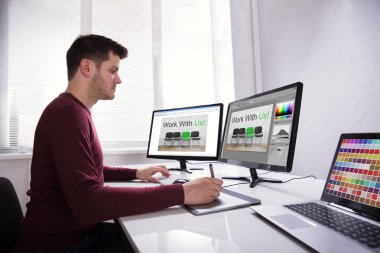 Genç erkek tasarımcı çizim grafik tablet bilgisayarda çalışırken yan görünüm