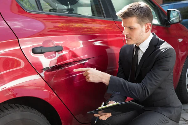 Insurance Agent Filling Insurance Form Near Damaged Red Car