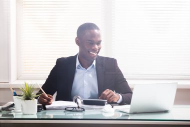 Ofiste fatura hesaplama Laptop bakarak mutlu Afrika işadamı