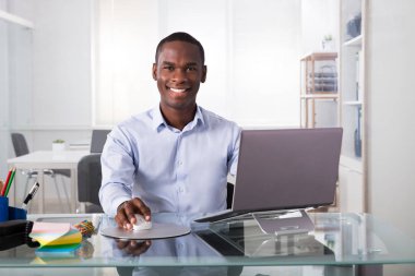 Portrait Of Young Smiling Businessman Using Laptop At Workplace clipart