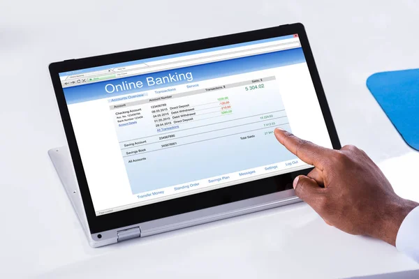 白い机の上のノート パソコンにオンラインバン キング フォームを指している実業家の手のクローズ アップ — ストック写真