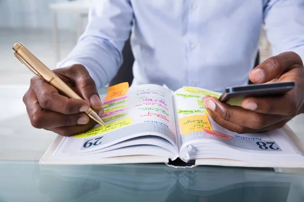 Närbild Affärsman Som Håller Mobiltelefon Skriva Schema Dagbok Med Penna — Stockfoto