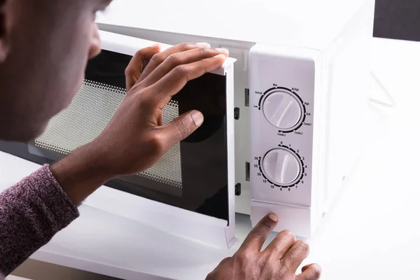 Close-up Of A Man Pressing Button Of Microwave Oven