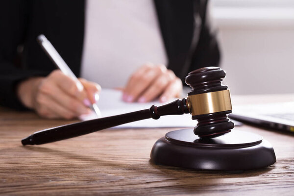 Крупный план "Молотка" перед судьей, работающим над документом
