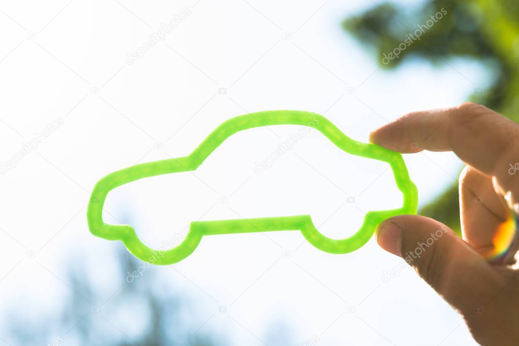 Person's hand holding outline of green eco car