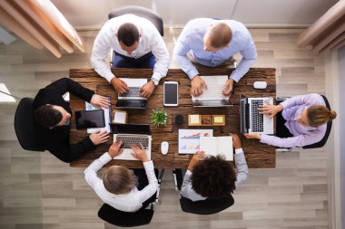 Group Of Businesspeople Working On Laptop Over Wooden Desk clipart