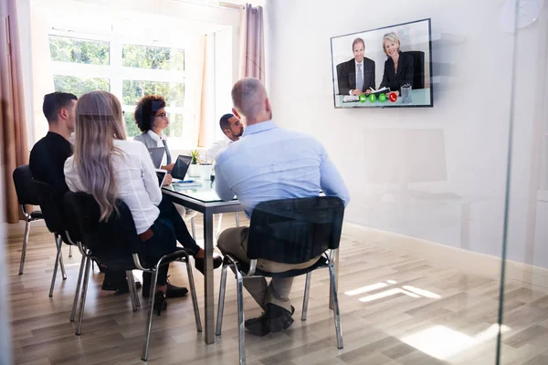 一群不同的商人看电视 而视频会议在会议室 — 图库照片