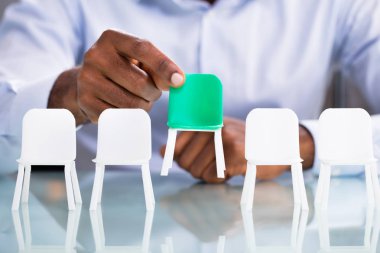 Yeşil beyaz sandalye koltuktan tutan işadamı