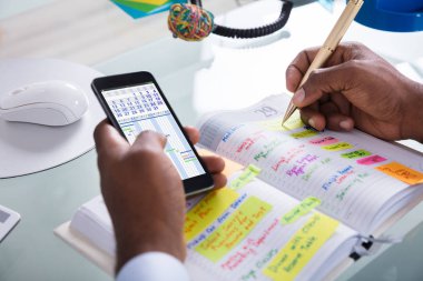 Gantt App ve takvim yazma programı ile cep günlüğü ile kalem tutan işadamı