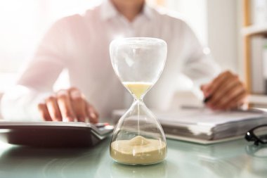 Bill bir kum saati ampuller ile çalışan kum arkasında hesaplama işadamı