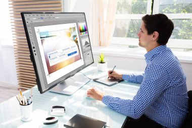 Grafik tablet kroki için bilgisayarda çalışırken genç erkek Editor'ı kullanma