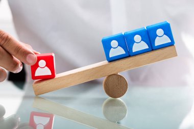 Tek kırmızı blok ve insan figürleri ile mavi bloklar arasında dengesizlik tahterevalli üzerinde gösterilen kişi